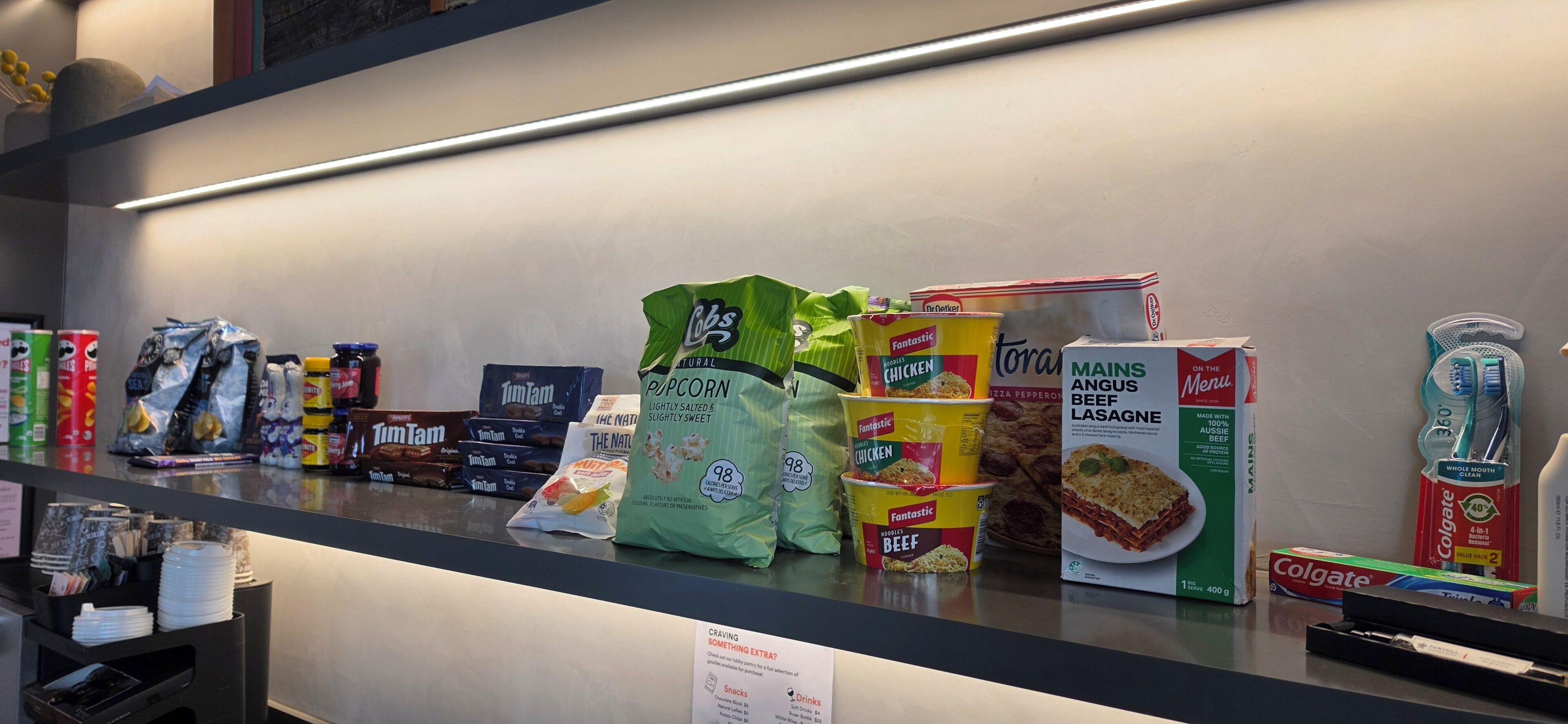 A grocery shelf stocked with various food items including snacks, canned goods, and beverages.