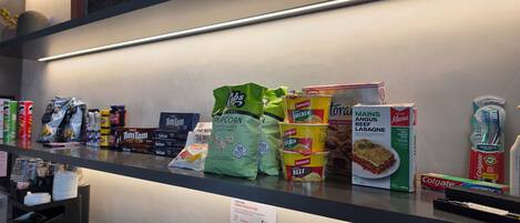 A grocery shelf stocked with various food items including snacks, canned goods, and beverages.