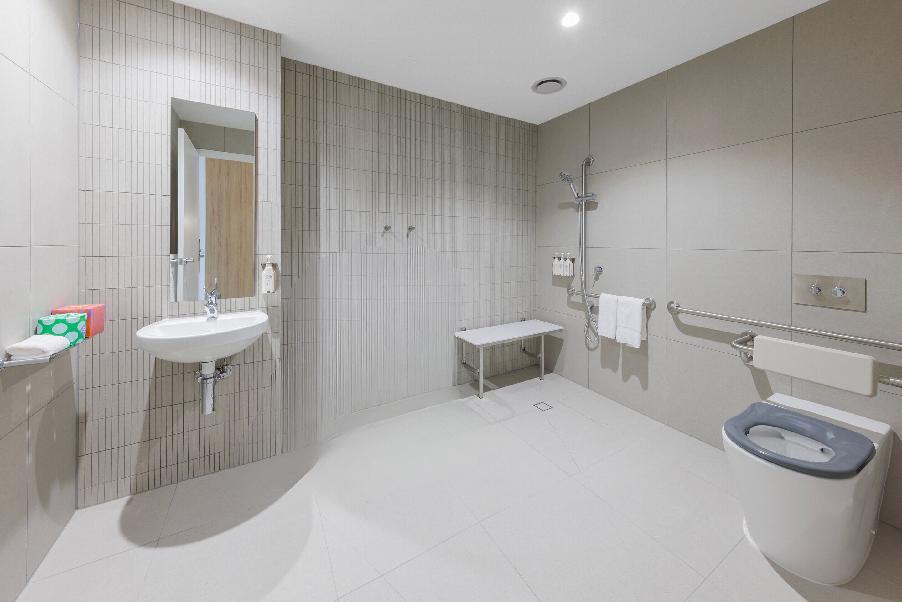 A modern bathroom with two sinks, a shower, and a toilet.