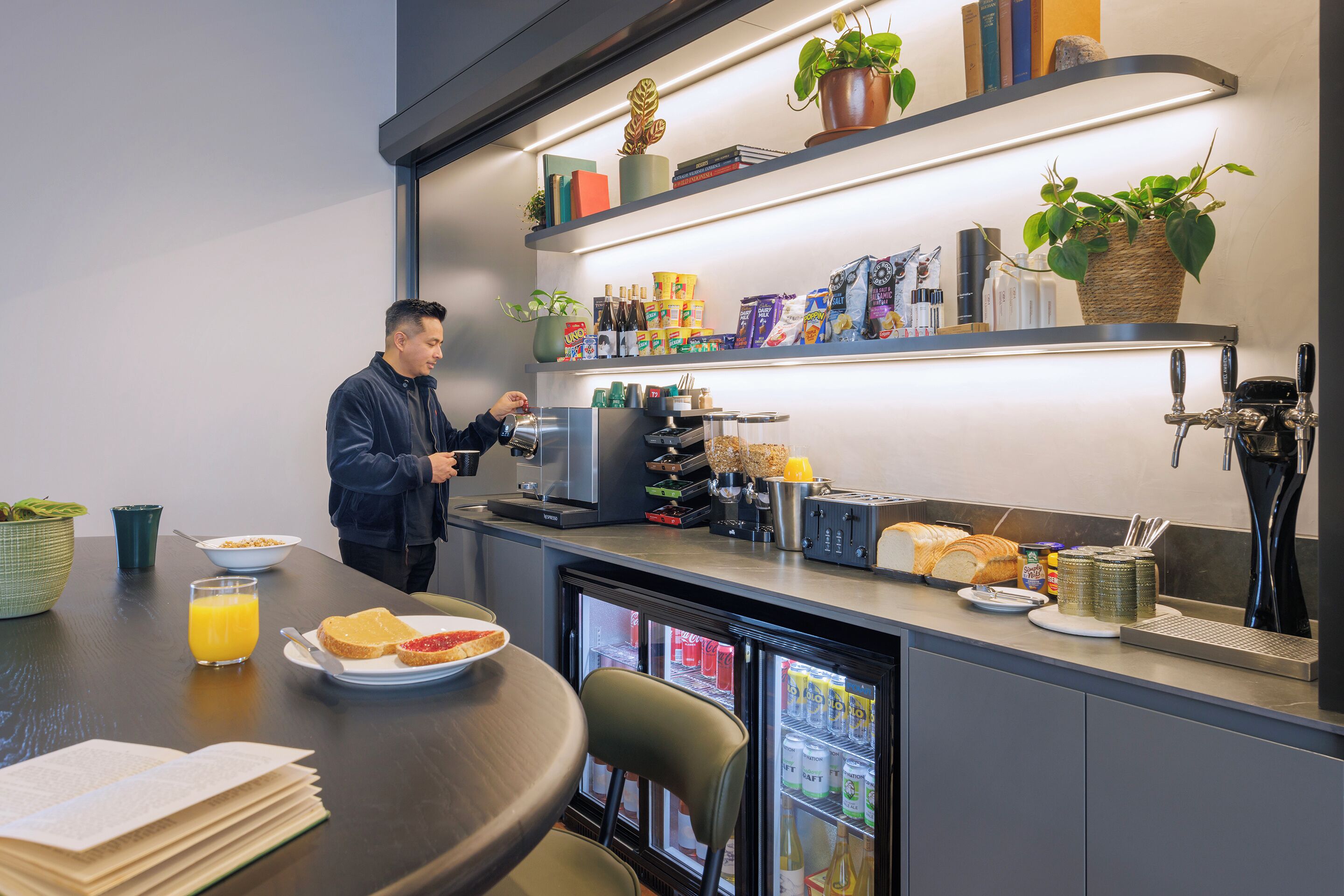 Una cucina moderna con frigorifero, macchina del caffè e prodotti per la colazione sul bancone.