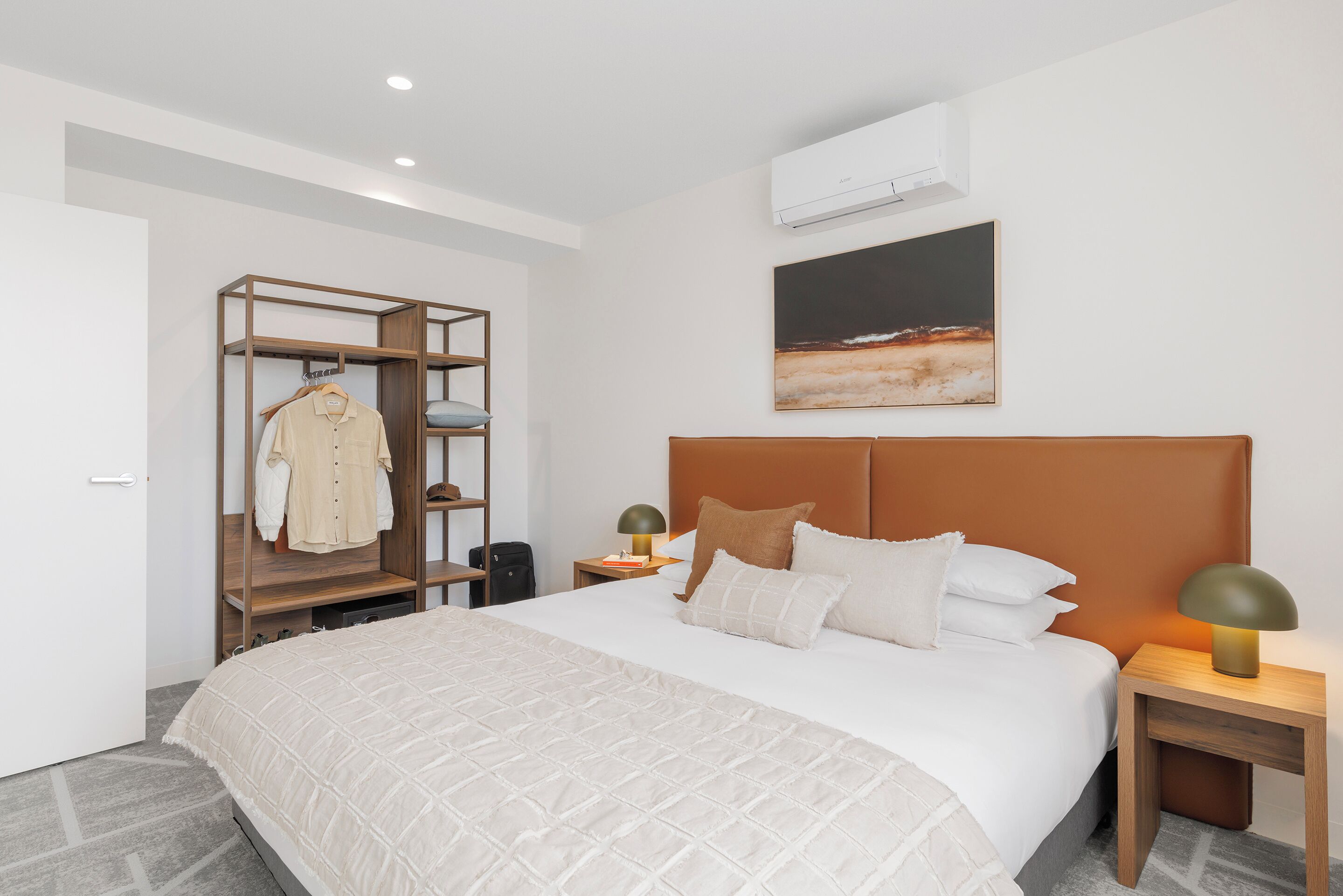 Ein modernes Hotelzimmer mit einem großen Bett, einem Holzschrank, einem Nachttisch mit Lampe und einem Bild an der Wand.