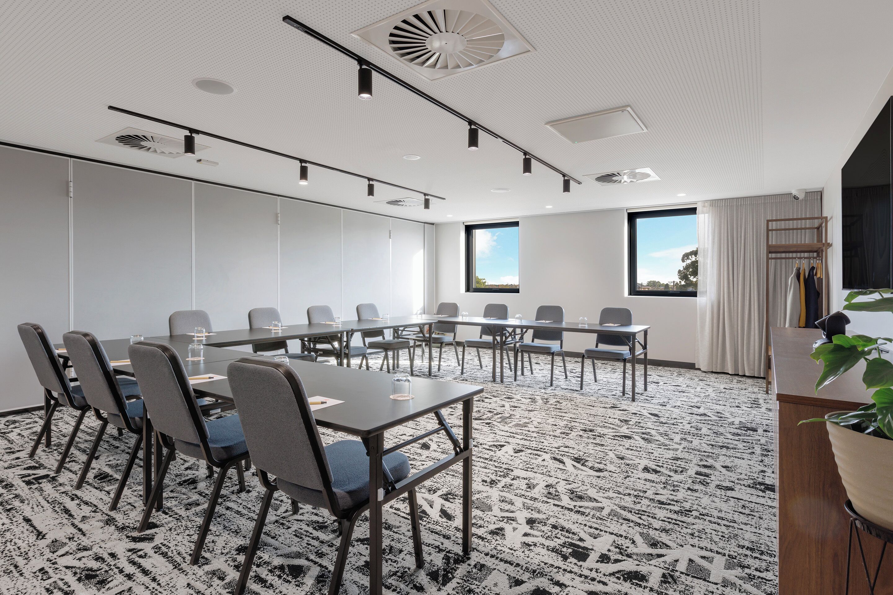 Un salón de conferencias con una larga mesa, sillas y piso alfombrado.