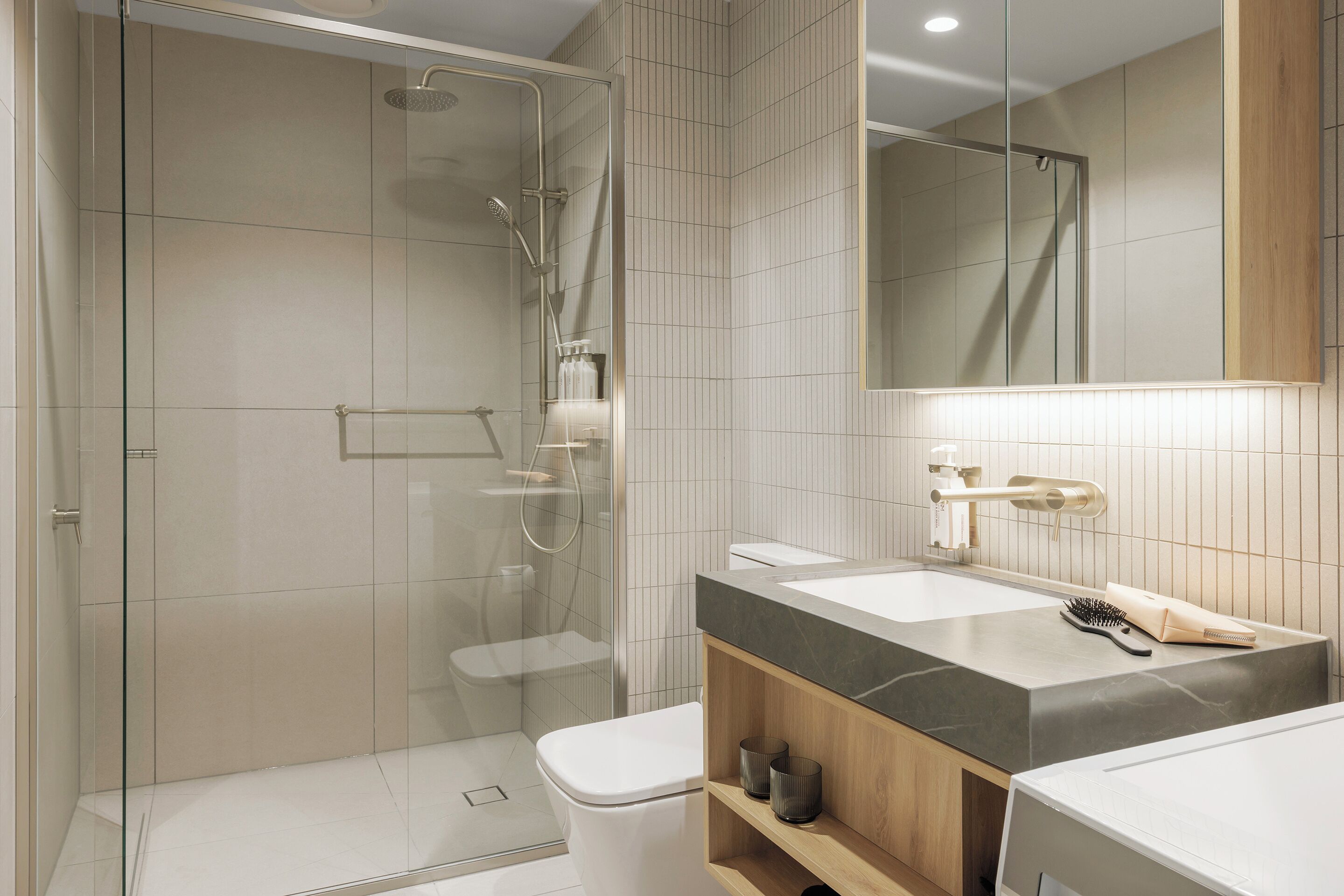 A modern bathroom with a glass-enclosed shower, a white toilet, a vanity with a marble countertop, and a mirror above the sink.