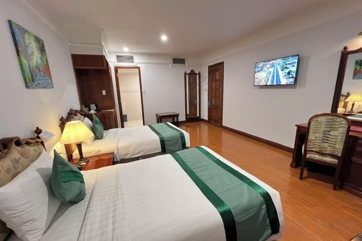 Habitació d'hotel amb dos llits, televisió, escriptori i una cadira.