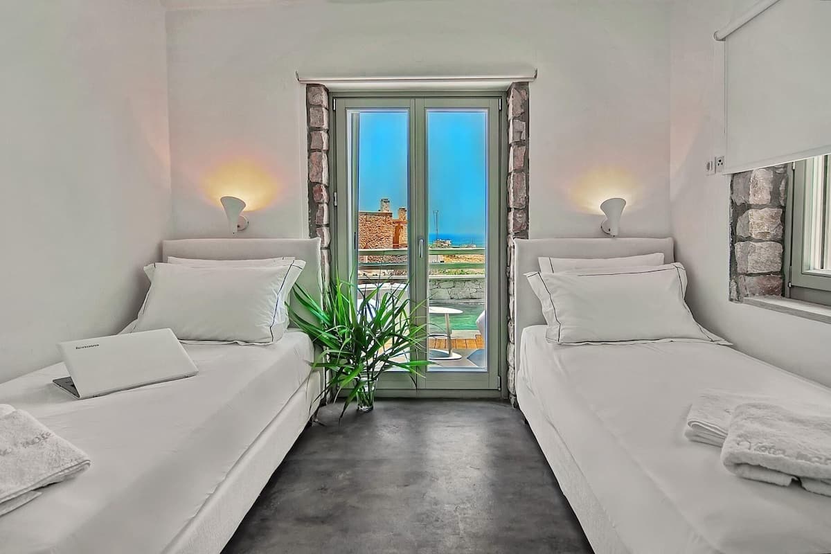 A room with two beds, a laptop, and a potted plant.