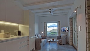 A modern kitchen with a built-in oven, a coffee machine, and a dining area with a table and chairs. - Vista mare villas (Sitia)
