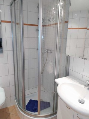 Une salle de bain moderne avec une douche à parois de verre, un lavabo blanc et des murs carrelés.
