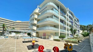 A multi-story hotel with a curved facade, outdoor seating area, and a pool.