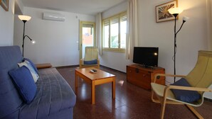 Ein Wohnzimmer mit einer Couch, einem Holztisch, einem Fernseher und einem Sessel.
