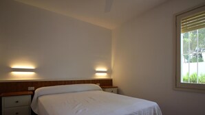 Ein Schlafzimmer mit einem Bett, zwei Nachttischen, einem Fenster mit Rollläden.