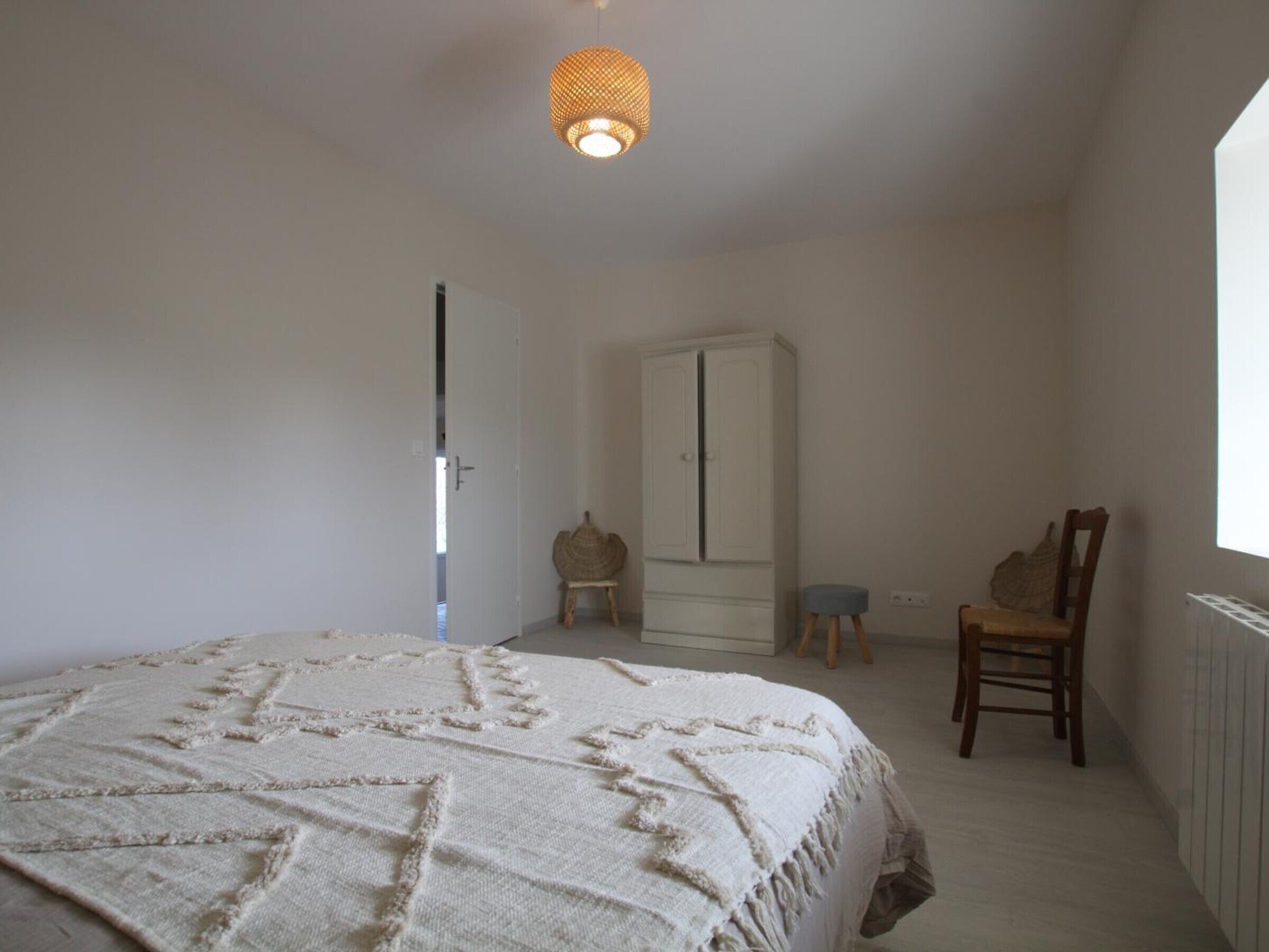 Una camera da letto con un letto, un armadio, una sedia e una lampada a sospensione.