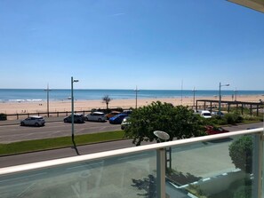 Ein Parkplatz mit Autos, einem Strand und blauem Himmel.