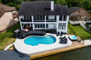 A two-story house with a swimming pool, outdoor seating, and a hot tub.