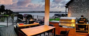 An outdoor patio with a grill, seating, and a view of the water.