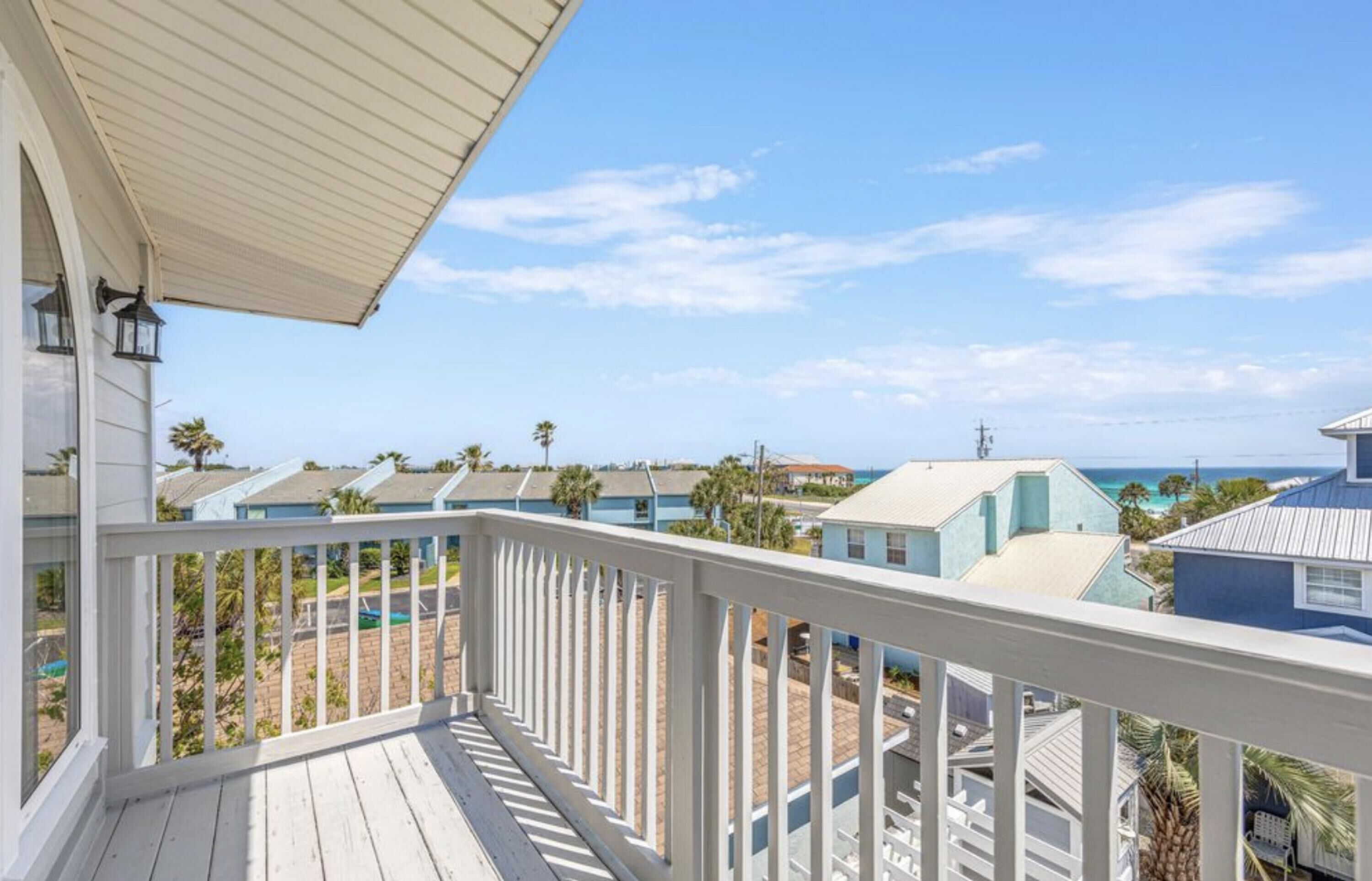 A balcony with a view of a beach and other houses.