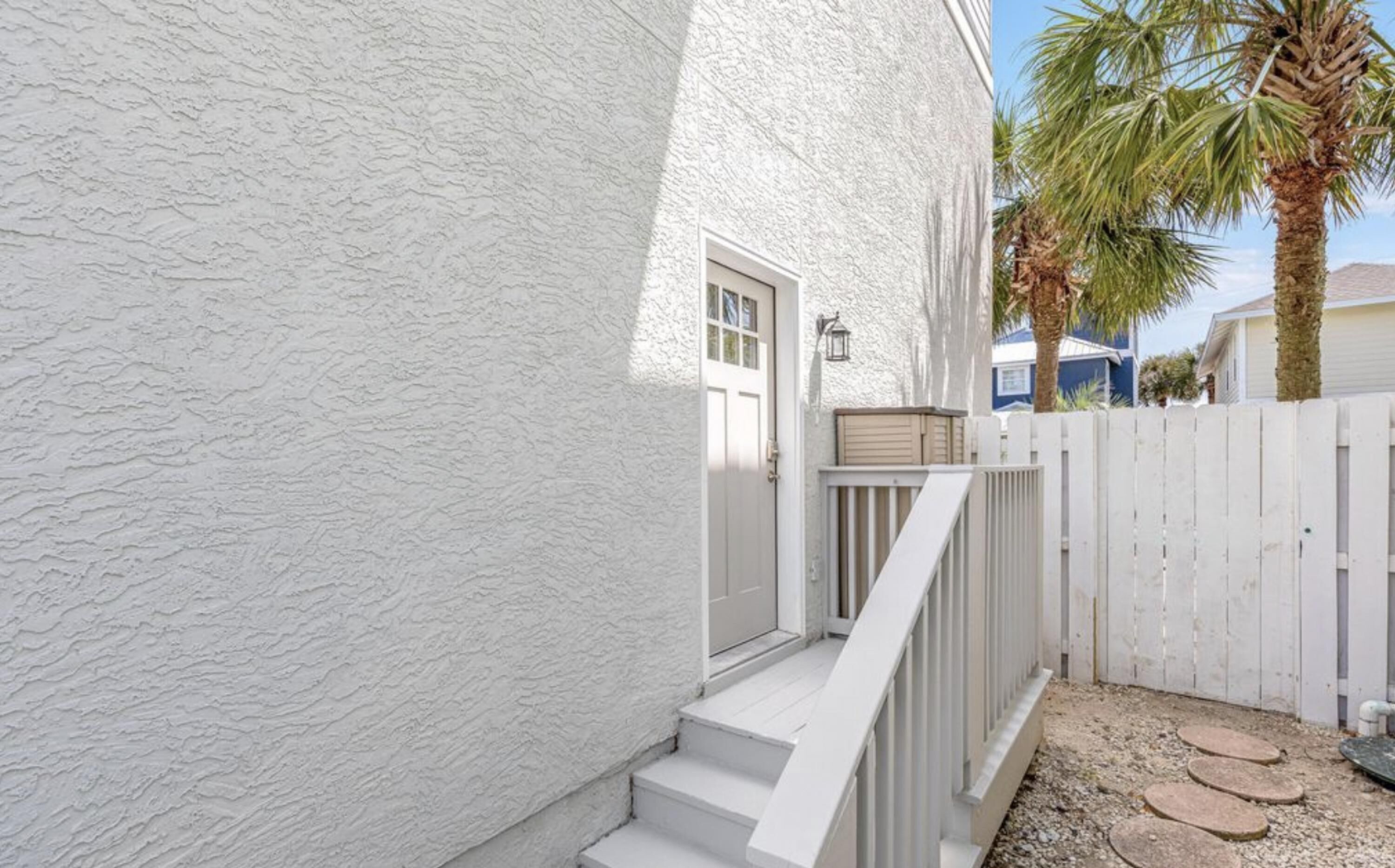 A white stucco building with a white door and a small porch with steps.