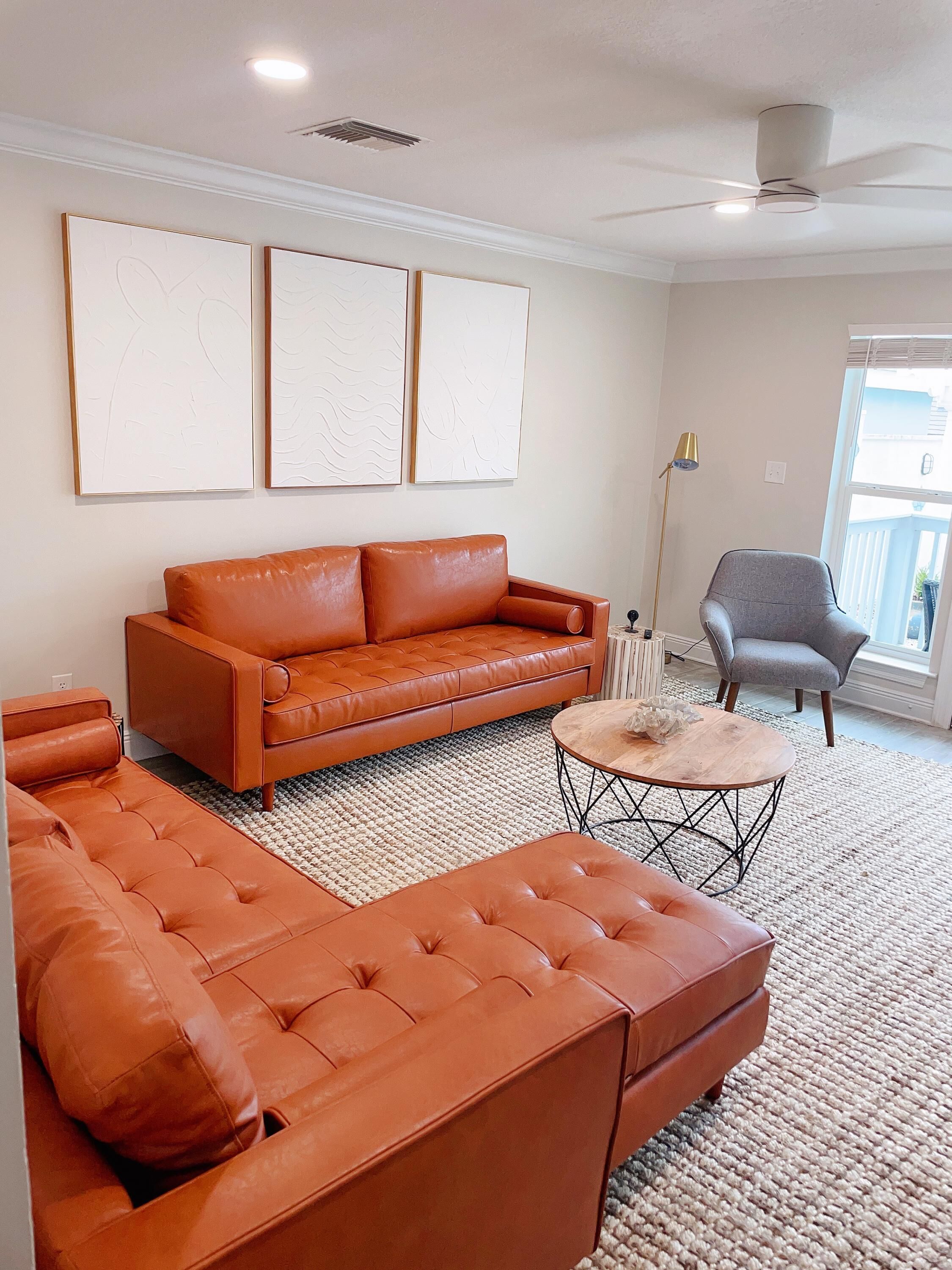 A living room with a sectional sofa, a gray armchair, a coffee table, and abstract wall art.