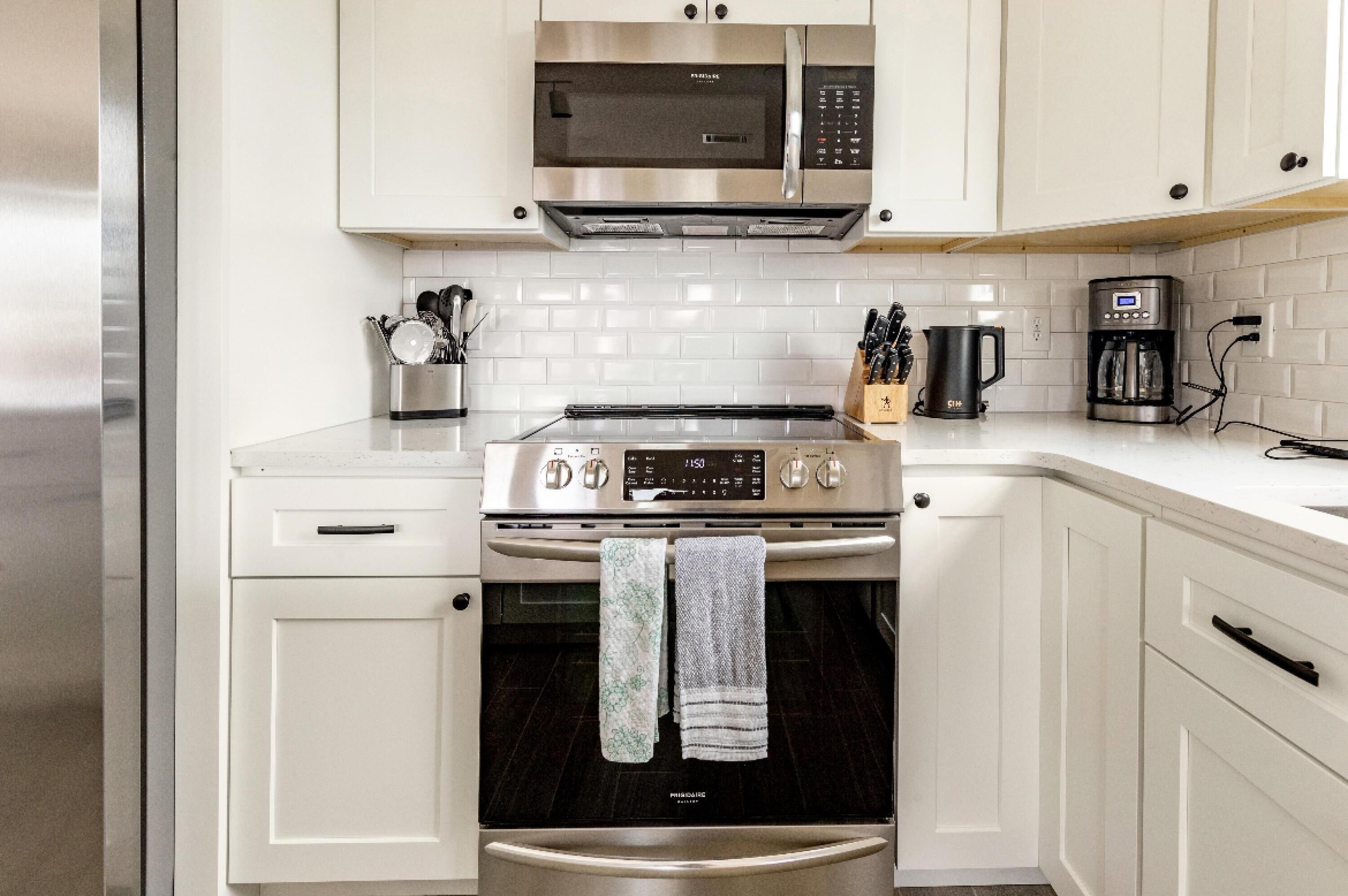 A kitchen with white cabinets, stainless steel appliances, and a coffee maker.