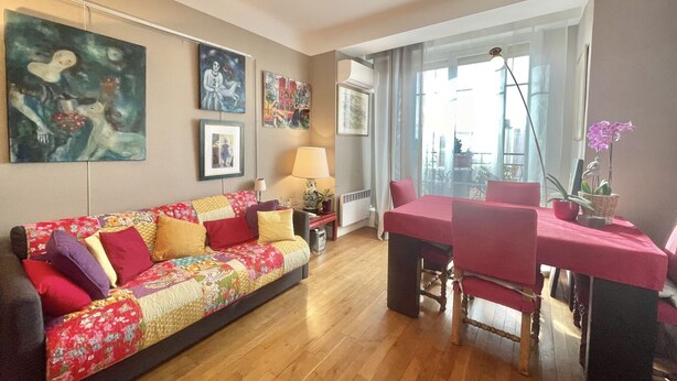 A living room with a sofa, a dining table with chairs, and artwork on the walls. - The Artist (Cannes)