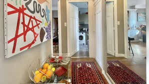 A hallway with a clear view of a kitchen area, a washing machine, and a dining area with a table and chairs. - The Artist (Cannes)