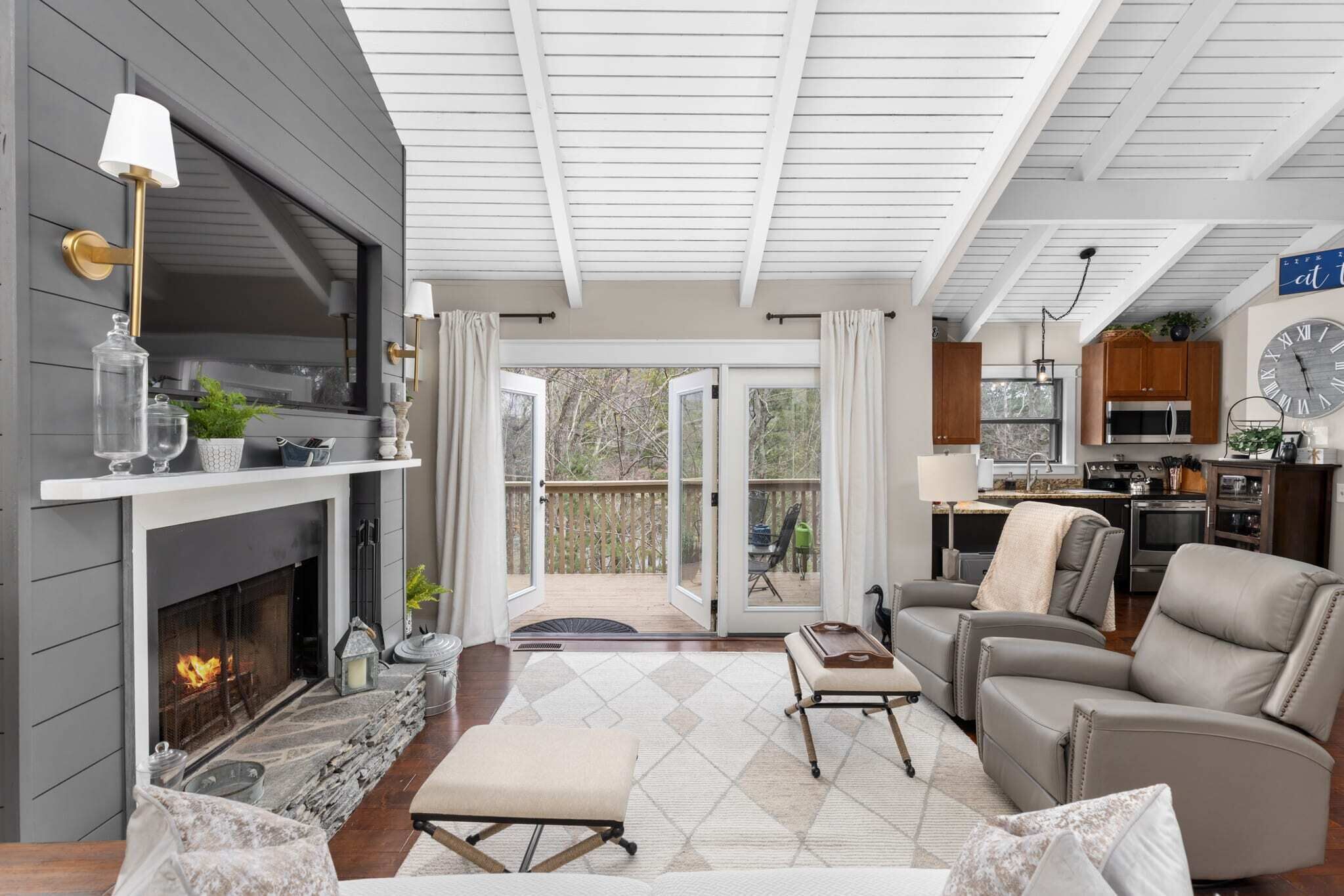 A cozy living room with a fireplace, comfortable seating, and a view to an outdoor deck.