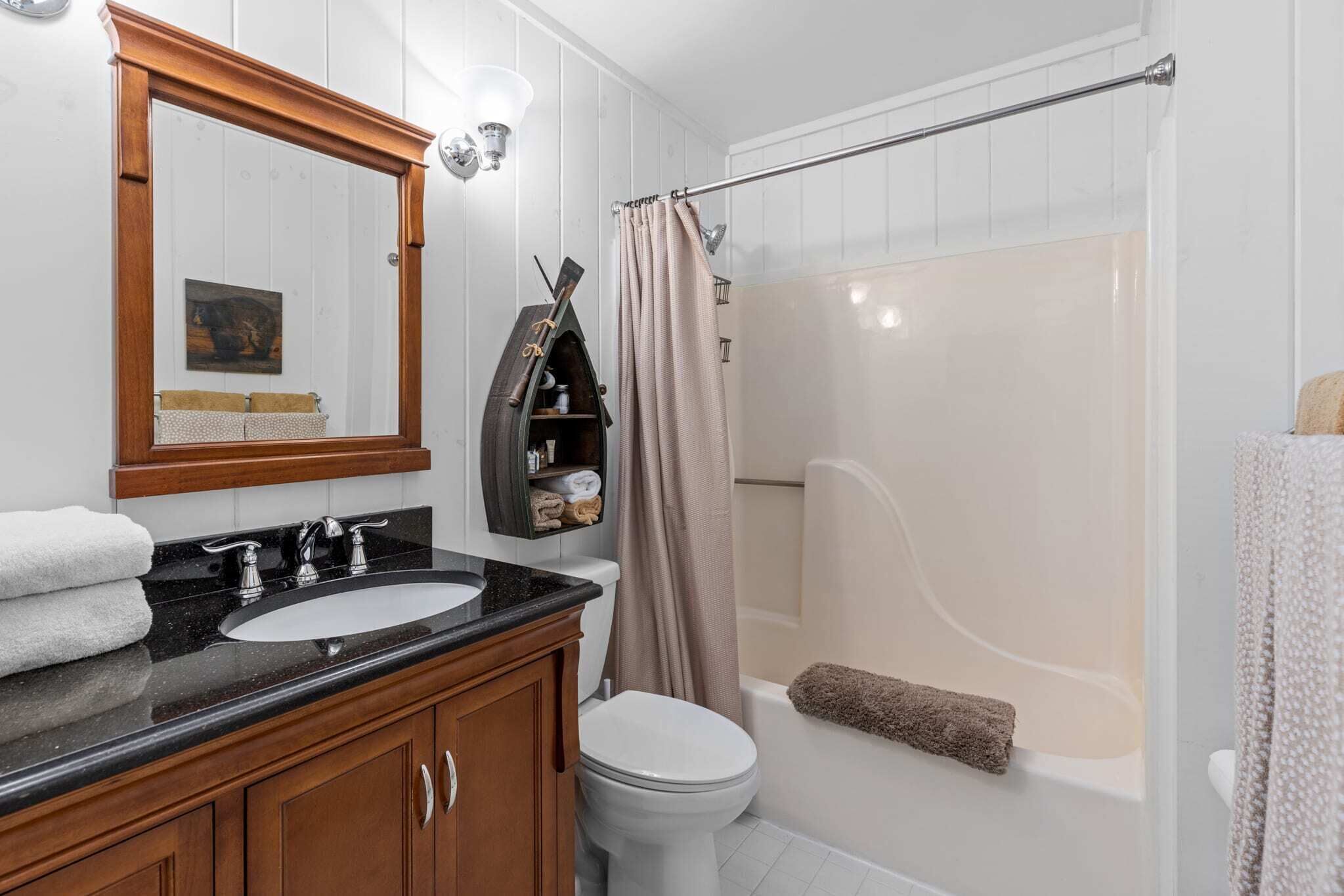 Un baño con tocador de madera, lavabo, inodoro y bañera.