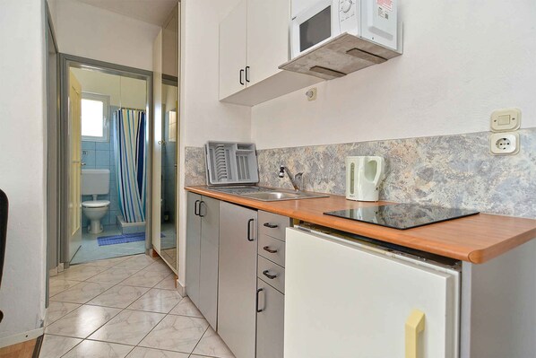 A compact kitchen with a microwave, kettle, and a small sink.