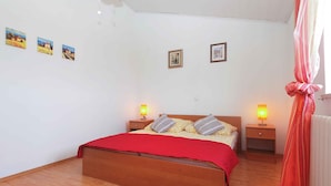 A bedroom with a wooden bed, two bedside tables with lamps, a red bedspread, and three framed pictures on the wall. - Holiday apartment with 2 bedrooms and terrace (Banjole)