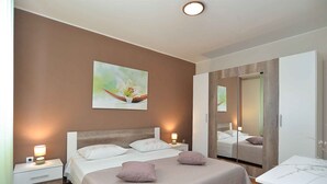 A bedroom with a bed, bedside tables, a mirror, and a painting on the wall. - Holiday apartment with air conditioning and large terrace (Pula)