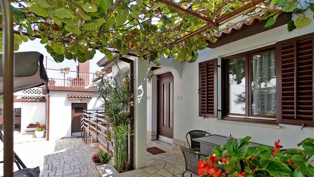 A patio area with a table and chairs, a door, and a balcony with plants. - Holiday apartment with air conditioning and large terrace (Pula)
