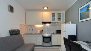 A compact kitchen with a sofa, dining table, and chairs, a microwave, oven, and a refrigerator. - Holiday apartment with air conditioning and large terrace (Pula)