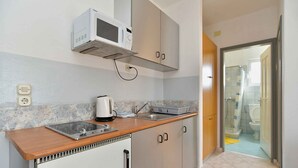 Een kleine keuken met een magnetron, waterkoker en spoelbak.
