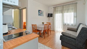 Een compacte leefruimte met een kitchenette, eethoek en een bank.