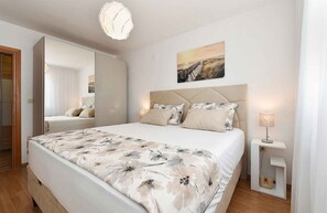 Relax in a serene bedroom with a large bed, bedside table, and a mirror.