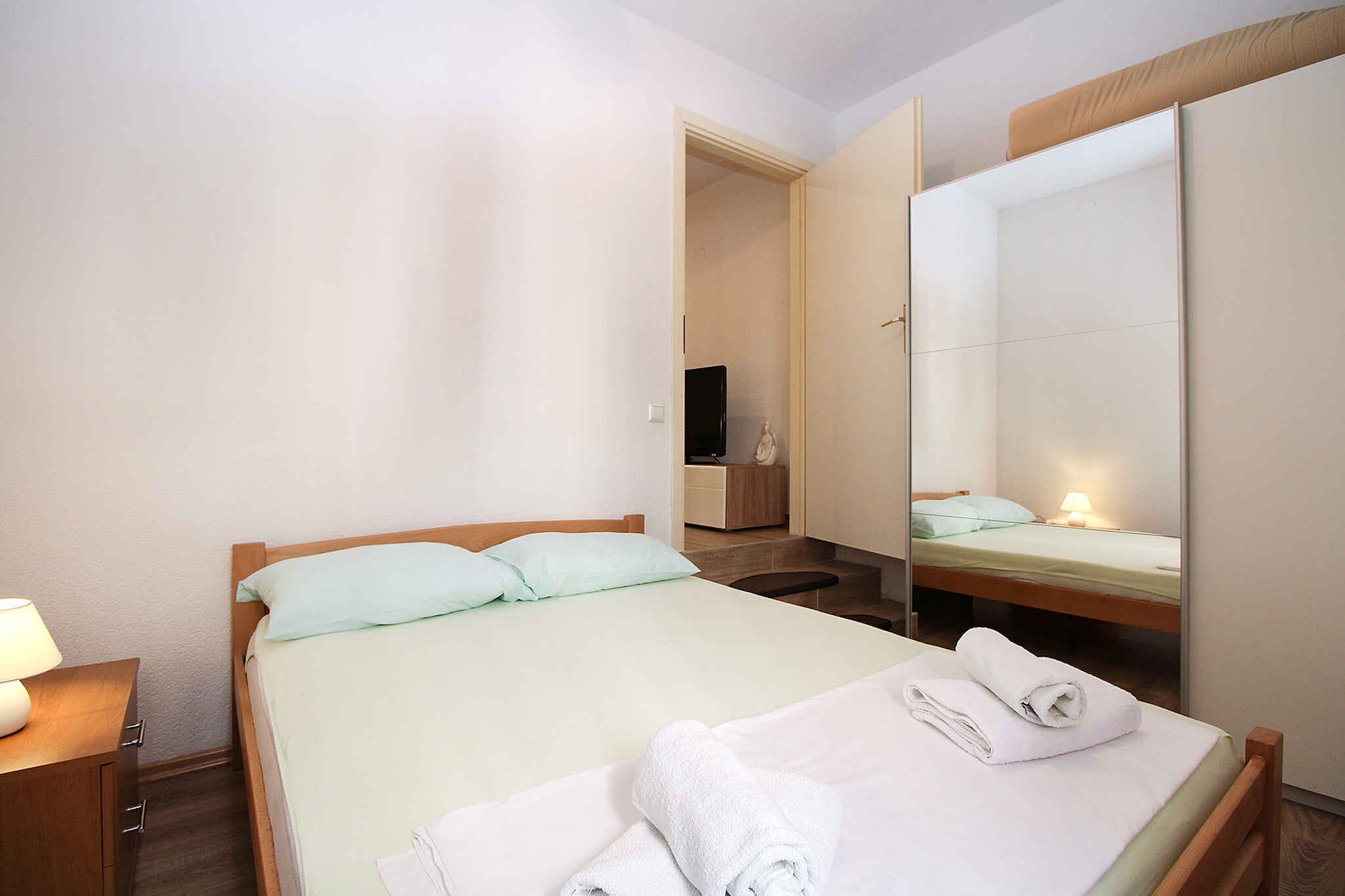 A hotel room with a bed, a nightstand, a mirror, and a bathroom visible through an open door.