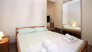 A hotel room with a bed, a nightstand, a mirror, and a bathroom visible through an open door. - Holiday apartment with air conditioning (Pula)