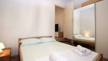 A hotel room with a bed, a nightstand, a mirror, and a bathroom visible through an open door.