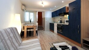 A compact living space with a sofa, a dining table, and a kitchenette. - Holiday apartment with air conditioning (Pula)