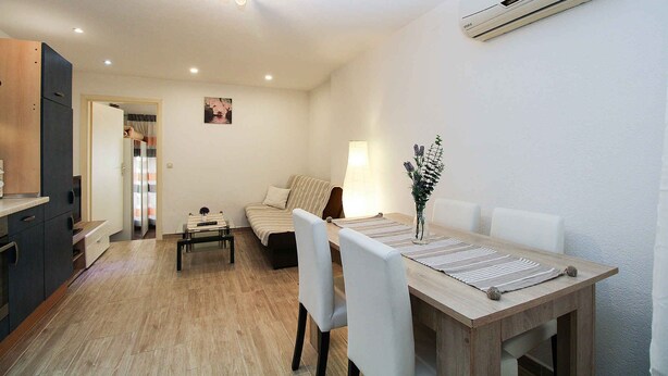A modern living room with a dining area, a sofa, a coffee table, and a lamp. - Holiday apartment with air conditioning (Pula)
