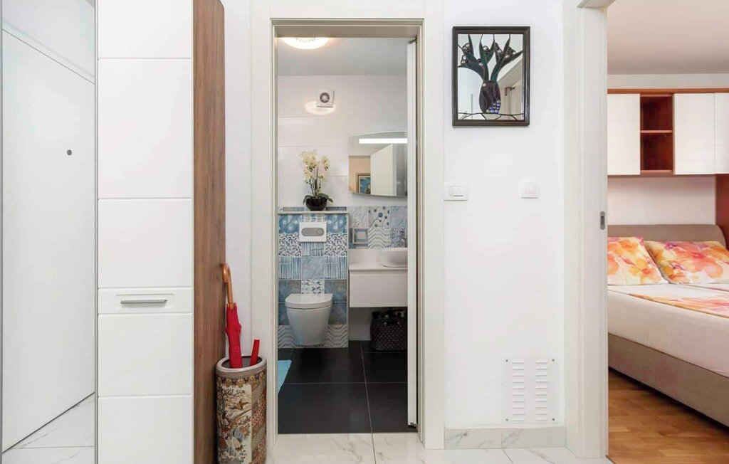Uma casa de banho moderna com sanita, lavatório e azulejos decorativos.