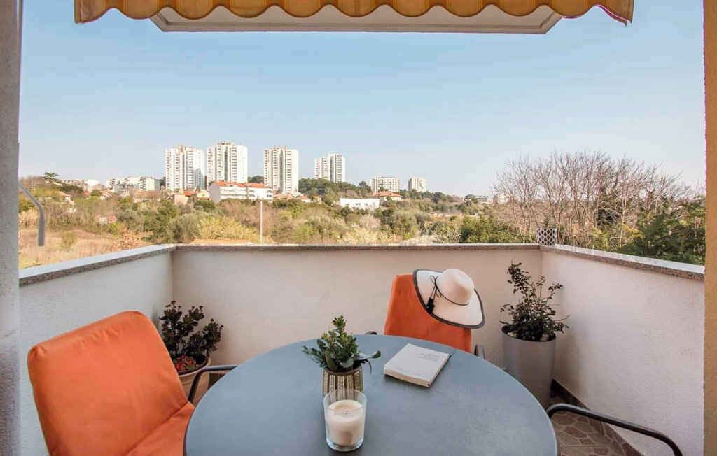 Een balkon met een tafel, stoelen en uitzicht op hoge gebouwen op de achtergrond.