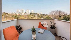 Un balcon avec une table, des chaises et une vue sur les immeubles de grande hauteur en arrière-plan.