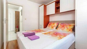 Une chambre à coucher comprenant un lit, une armoire et une porte donnant sur une autre pièce.