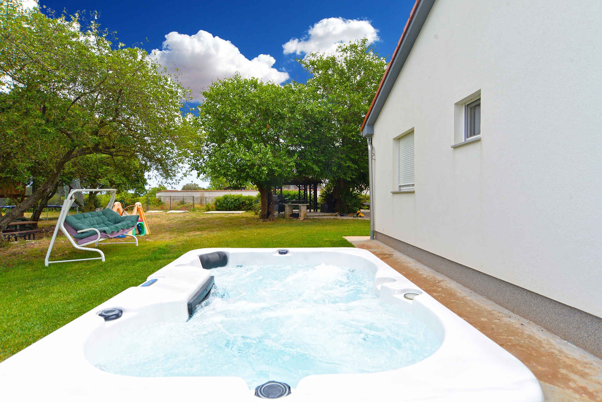 A hot tub in a backyard with a lawn chair and a swing set.