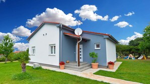 A two-story house with a red roof, a satellite dish, and a small garden with potted plants. - Holiday home with swimming pool on a large estate (Pula)