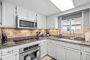 Een moderne keuken met witte kasten, een magnetron, een broodrooster en een spoelbak.