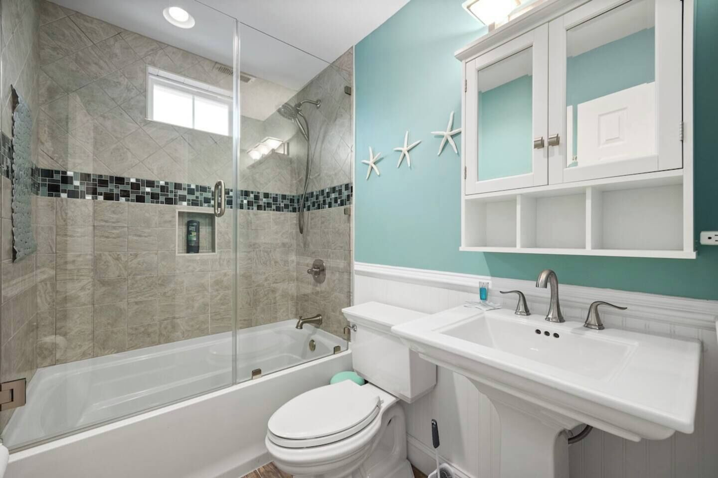 A bathroom with a glass-enclosed shower, a white toilet, and a sink with a mirror above.