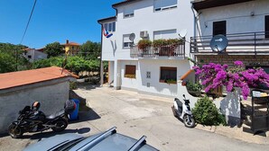 A two-story building with balconies, a parked scooter, and a motorcycle. - Holiday apartment with air conditioning with terrace in modern apartment (Pula)