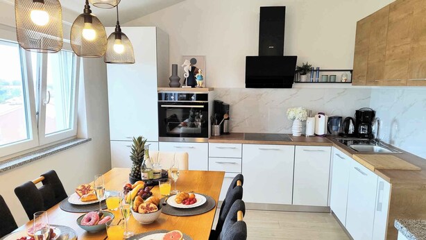 A modern kitchen with white cabinets, a wooden countertop, and a built-in oven. - Holiday apartment with air conditioning with terrace in modern apartment (Pula)