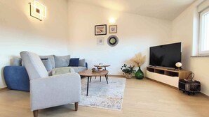 A modern living room with a sofa, armchair, coffee table, and TV. - Holiday apartment with air conditioning with terrace in modern apartment (Pula)